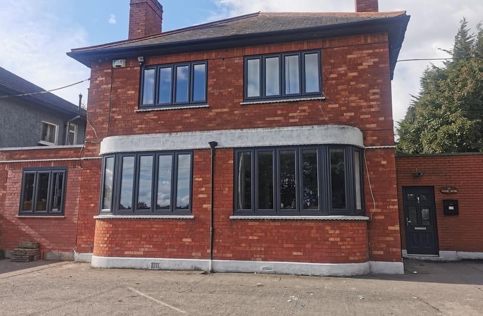 Red-brick house in Dublin with new anthracite grey bay windows and a navy composite front door