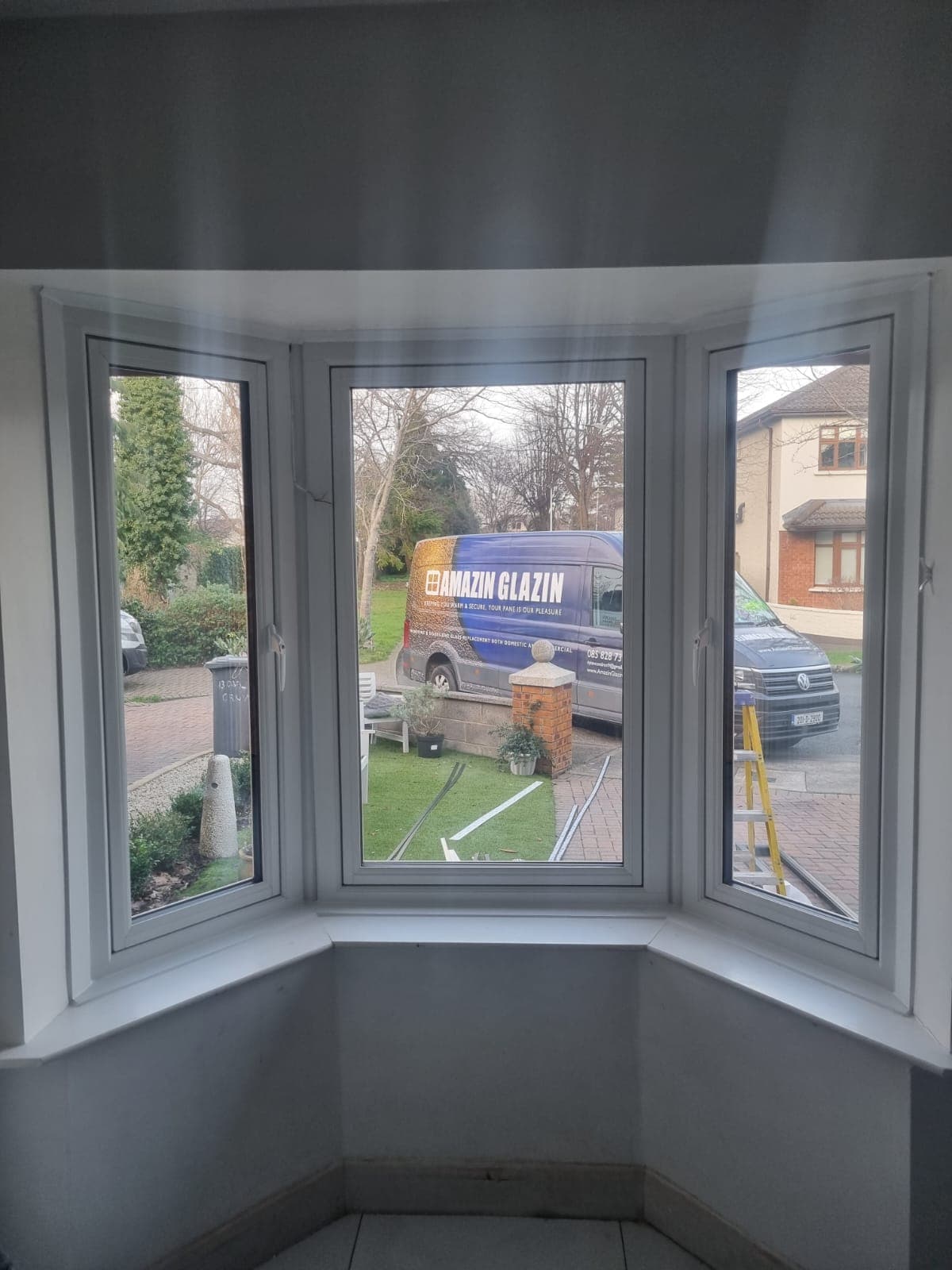 Interior view of a new white uPVC triple bay tilt and turn window, with the Amazin Glazin van visible outside