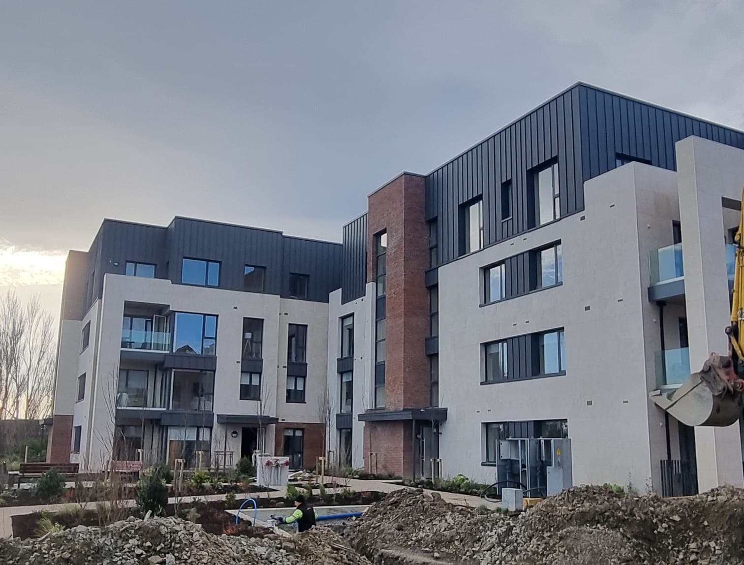 Apartment development during window installation, with site excavator visible