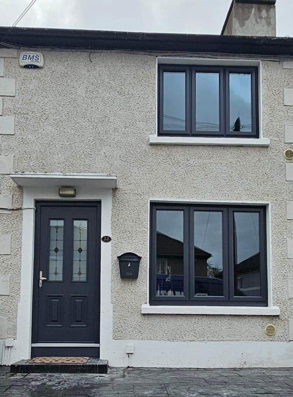 Anthracite grey symmetrical windows and composite front door on a rendered house