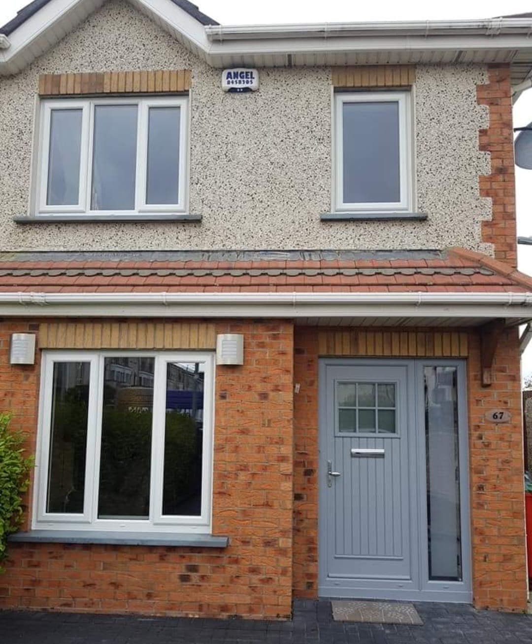 White uPVC casement windows and a grey composite front door on a red-brick house