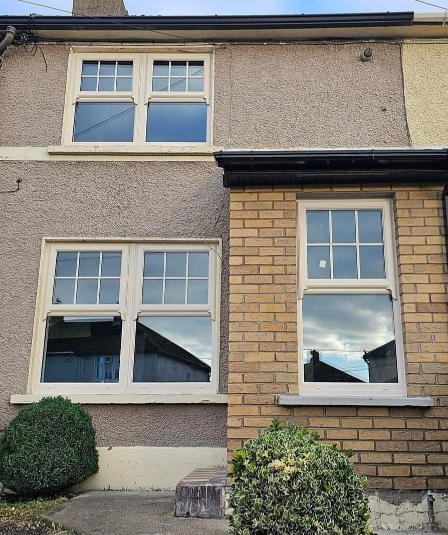 Cream mock sash windows on a two-tone render and brick terraced house
