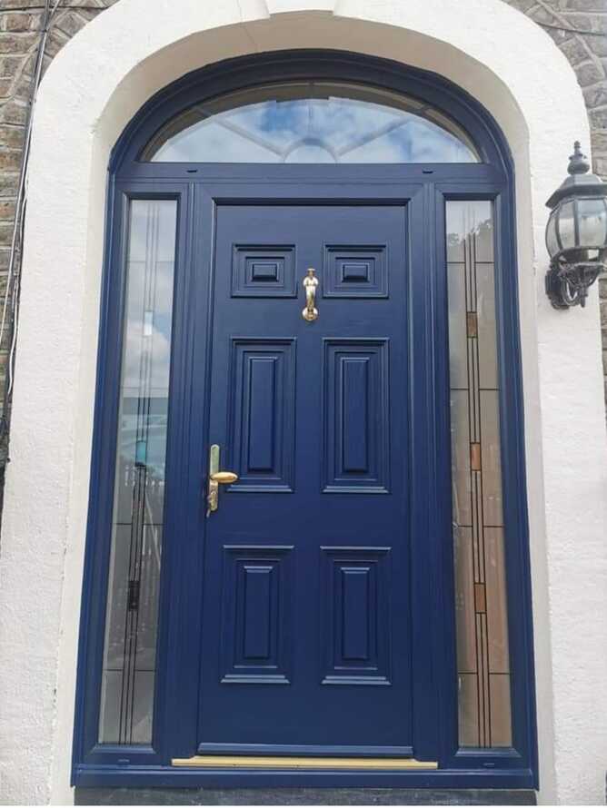 Navy arched composite front door with a decorative glass fanlight and brass hardware